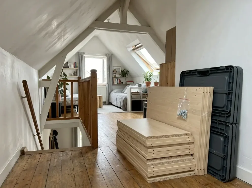Disassembled flat-pack furniture and collapsible bins showcasing clever small attic apartment ideas for frequent movers.